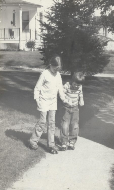 Photo of Kirsten Sutherland teaching her brother Warren how to skate. 1975