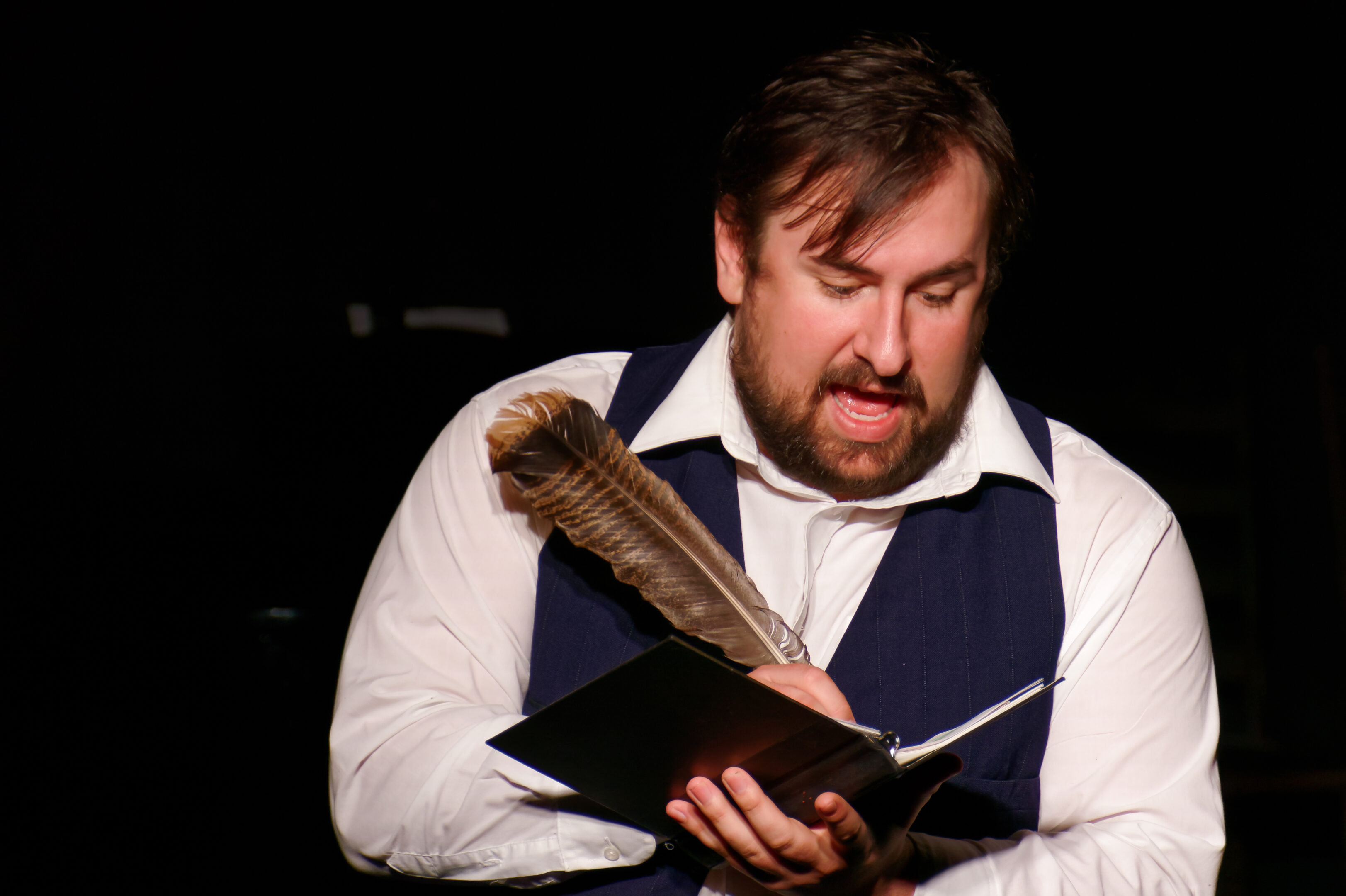 2023-Treasure Play-Trevor Baty writing with a feather pen as fictional journalist Charles Page