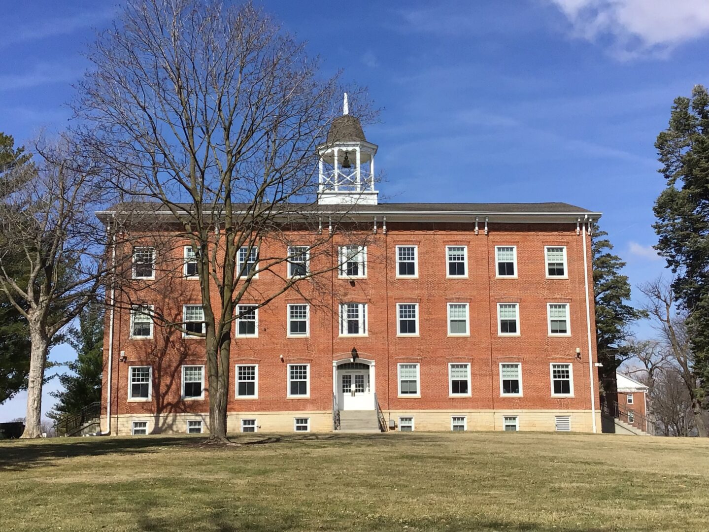 3+ story large red brick college classroom building known as College Hall.  Has a bell tower on the top center of building.