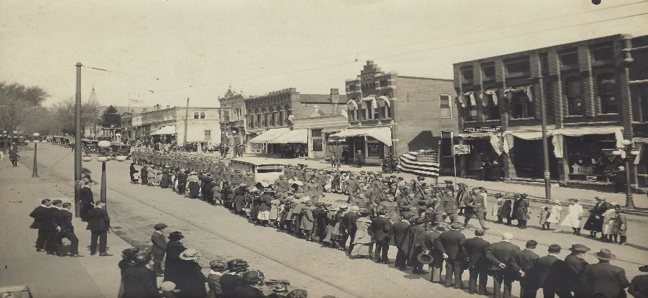 1921 black and white photo of a military parade marching on Main St., Mount Vernon, IA.