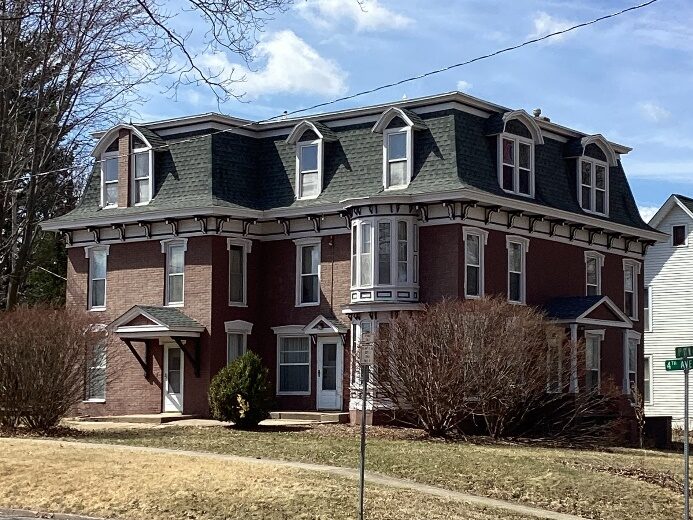 3-story red brick home with a mansard roof.  Example of a Second Empire style home.
