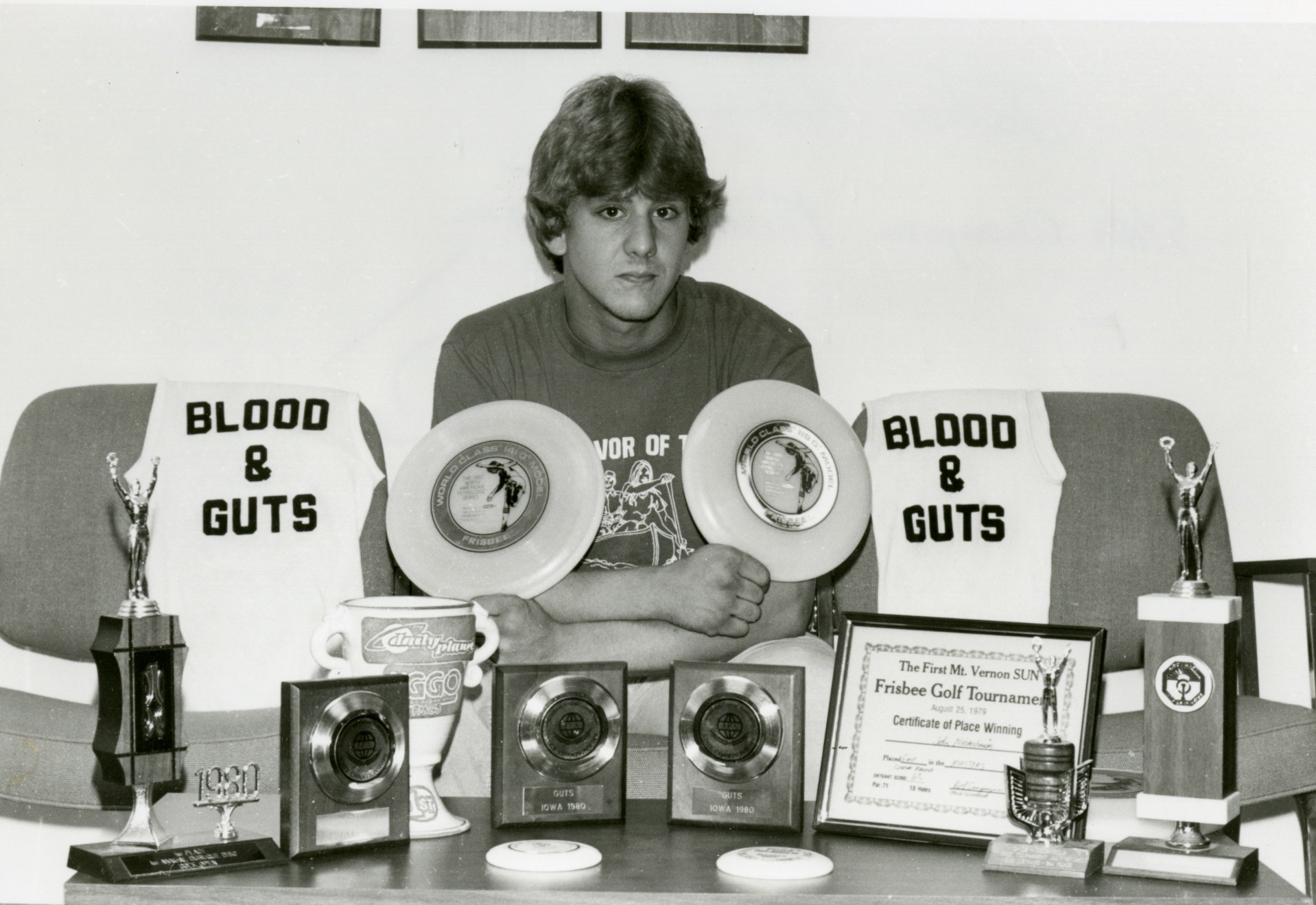 Photo of John Niederhauser sitting with his trophies.