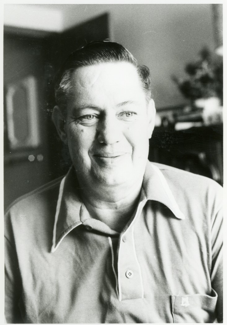Black and white photo of Dale Travis smiling.