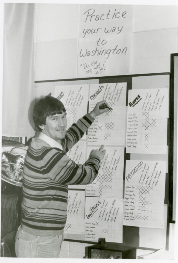Black and white photo of Mount Vernon Band Director Don Stine marking off people who have practiced their instruments in preparation for the band trip to Washington D.C.