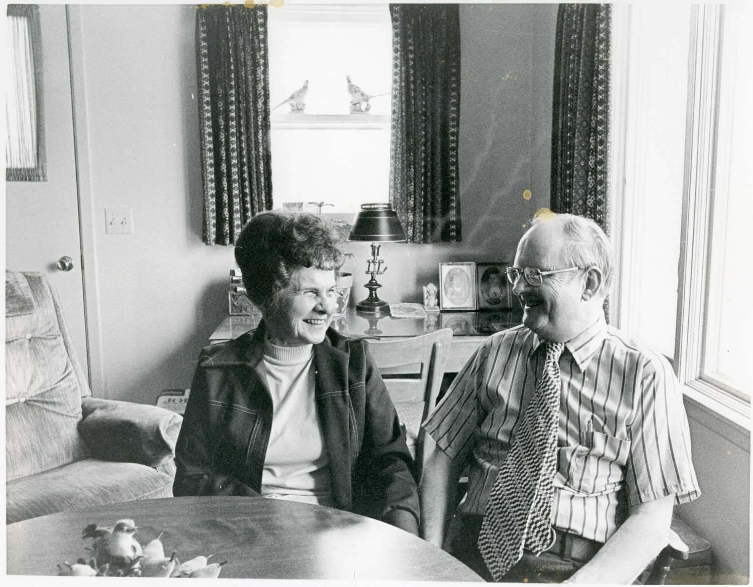 Black and white photo of Carrol and Bonnie Stoll smiling at each other.